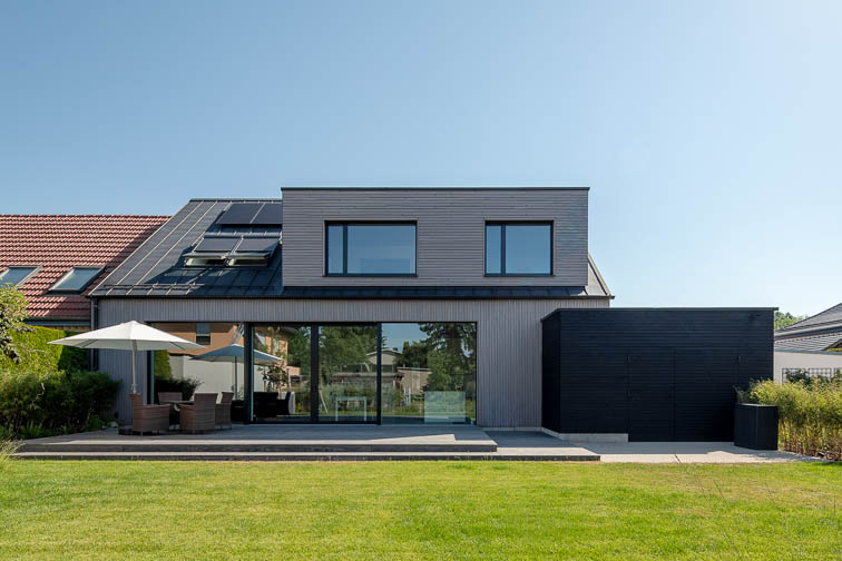 Gartenansicht einer Doppelhaushälfte in Holzbauweise in Leipzig-Stötteritz. Große Fensterflächen öffnen den Wohnraum zum Garten