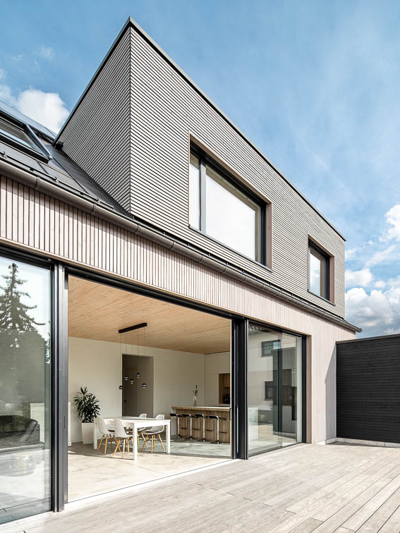 Außenperspektive der Gartenseite mit geöffneter Hebe-Schiebeanlage und Holzterrasse